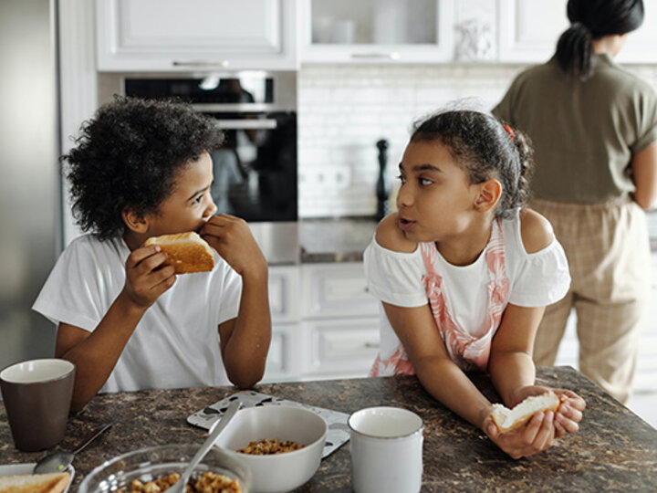 Siblings talking at table.