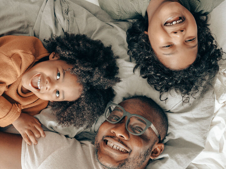 Family on bed smiling up at camera.